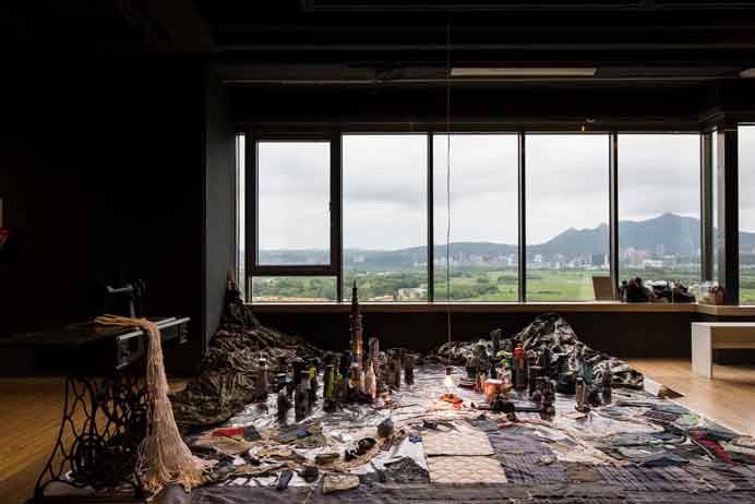 Kuo I-Chen  郭奕臣  -  Installation  -  Antique sewing machine, recycled fabric, PET bottle, electric motor, airplane model, light bulb, aerial photo of 1965 Taipei printed on canvas  -  400 x 375 cm  -  2021